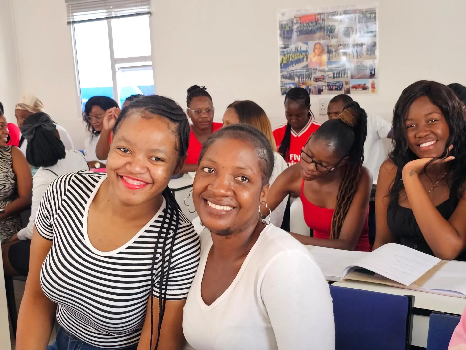 Group of PMT students in a classroom, smiling at camera, books open.