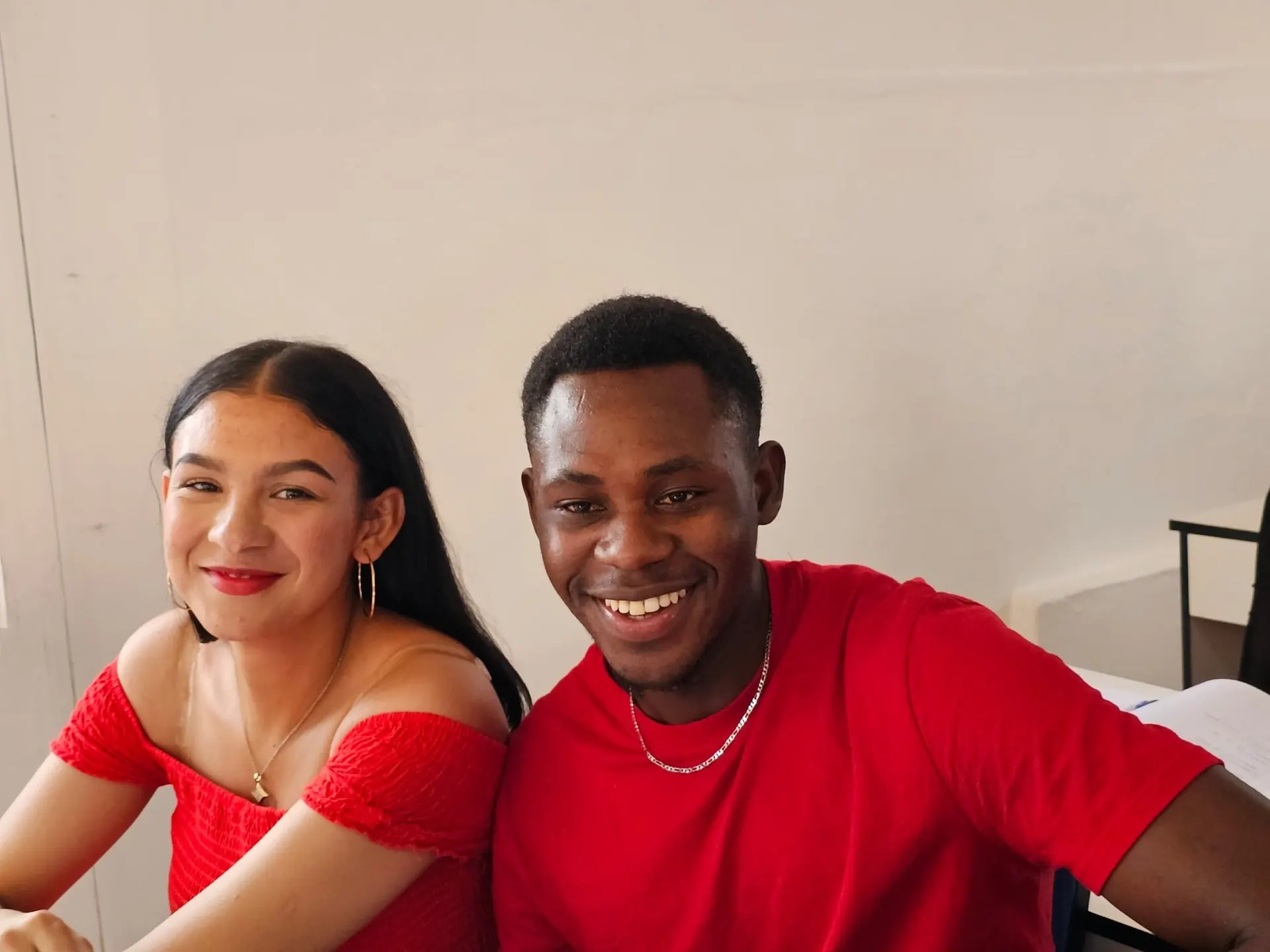 A woman in red and a man in red sitting side by side, smiling — campus ceremony.