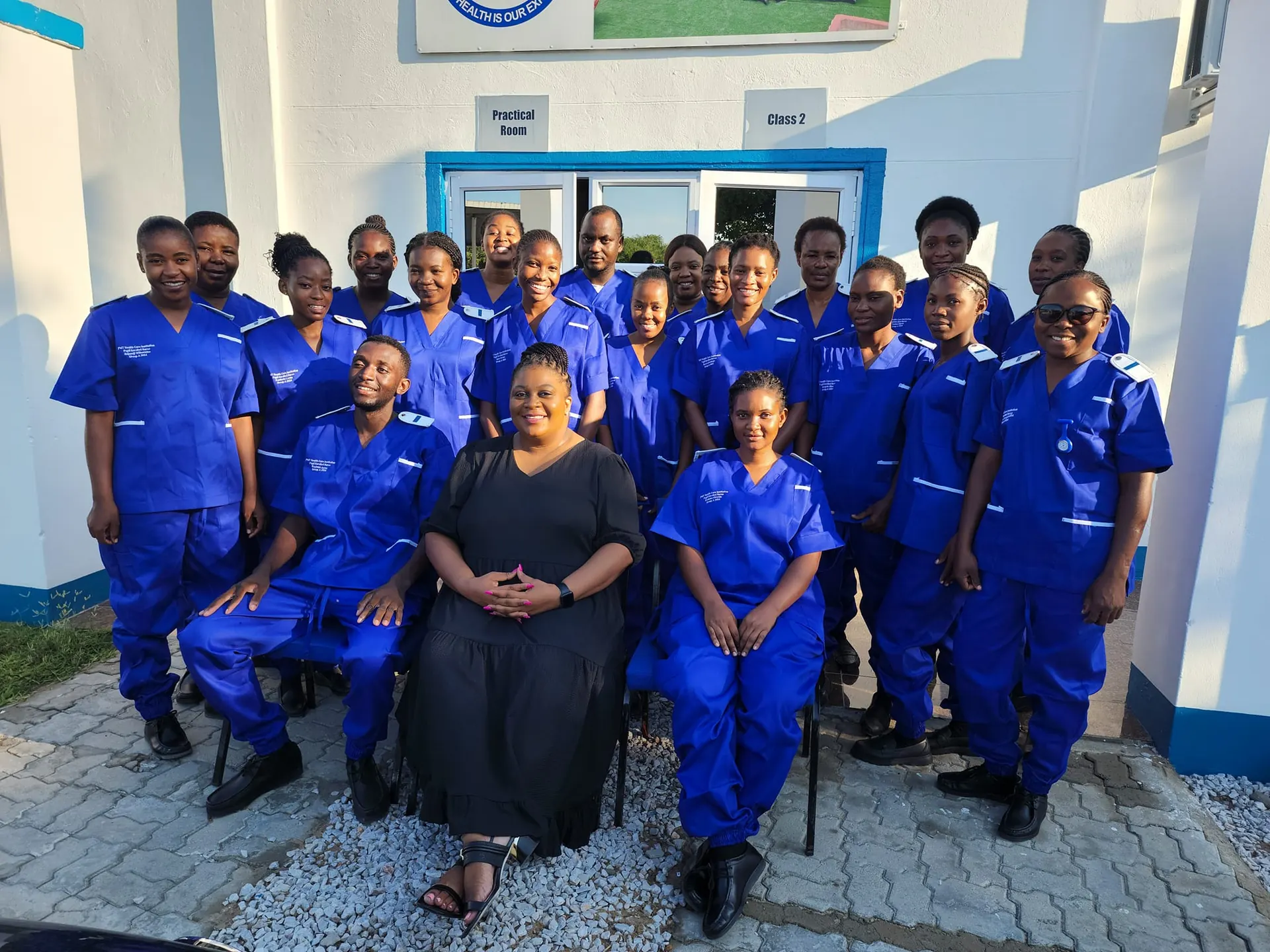 Group of PMT students in blue scrubs outside the Practical Room and Class 2.