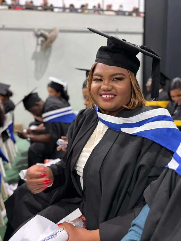 Graduate smiling at graduation ceremony.